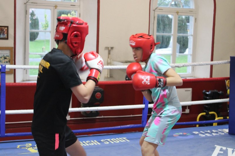 Two young boxers in red headgear working in the ring
